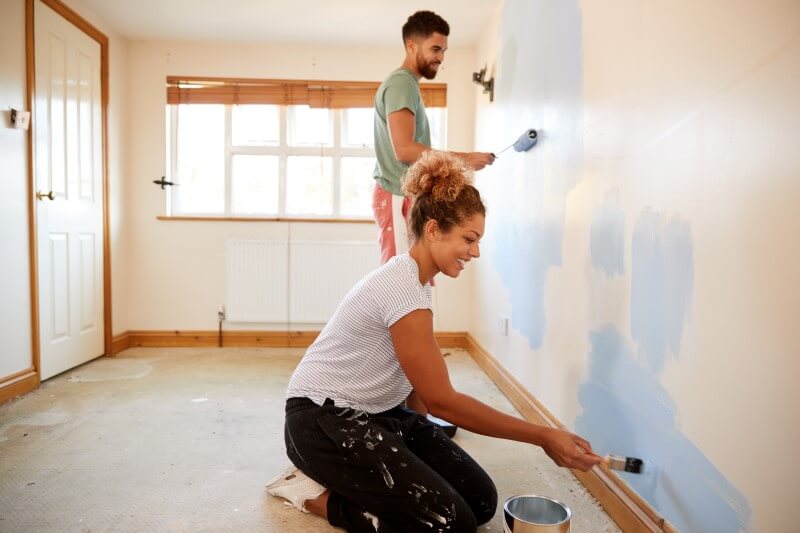 Foto de um jovem casal pintando as paredes de um quarto | Como pintar um apartamento | Guia da Tenda | Blog da Tenda