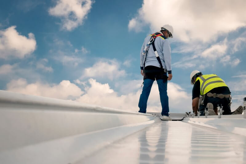 Foto de dois homens mexendo no telhado | Colmo é feito um telhado de um prédio | Guia da Tenda | Blog da Tenda