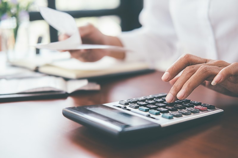 Foto de uma mulher calculando contas na calculadora | O que é subsídio e como usar o benefício para comprar a casa própria | Guia da Tenda | Blog da Tenda