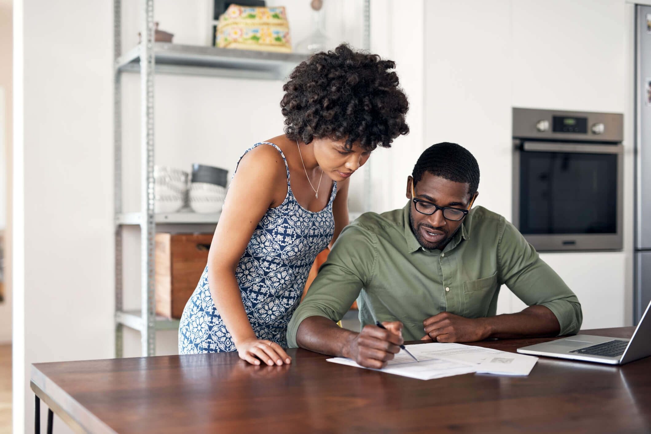 Foto de um homem e mulher avaliando documentos ao lado de um notebook | Quais documentos para usar o FGTS para comprar uma casa? | Minha Casa Minha Vida | Blog da Tenda