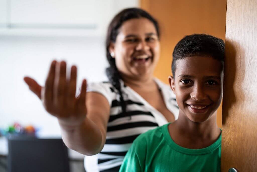 Mãe e filho sorriem enquanto convidam observador a entrar dentro do apartamento | Primeiro Apartamento | Guia da Tenda | Blog da Tenda
