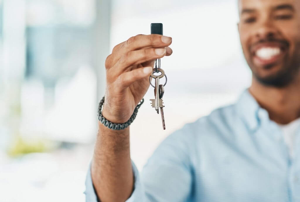 Homem sorri enquanto carrega chave de casa | Diferenciais Tenda | Guia da Tenda | Blog da Tenda