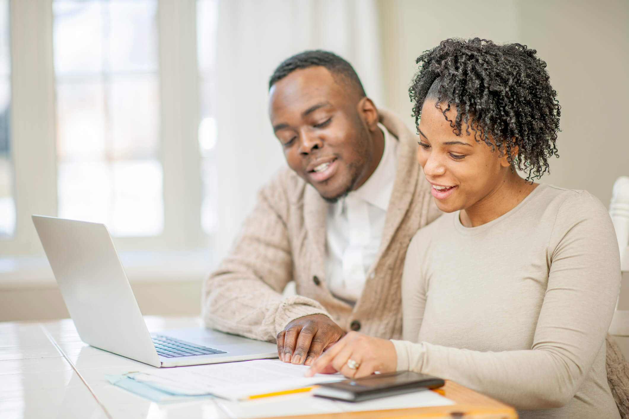 Qual é a melhor opção de amortização? | Em uma mesa com notebook, homem e mulher avaliam documento | Trilha da Conquista | Blog da Tenda