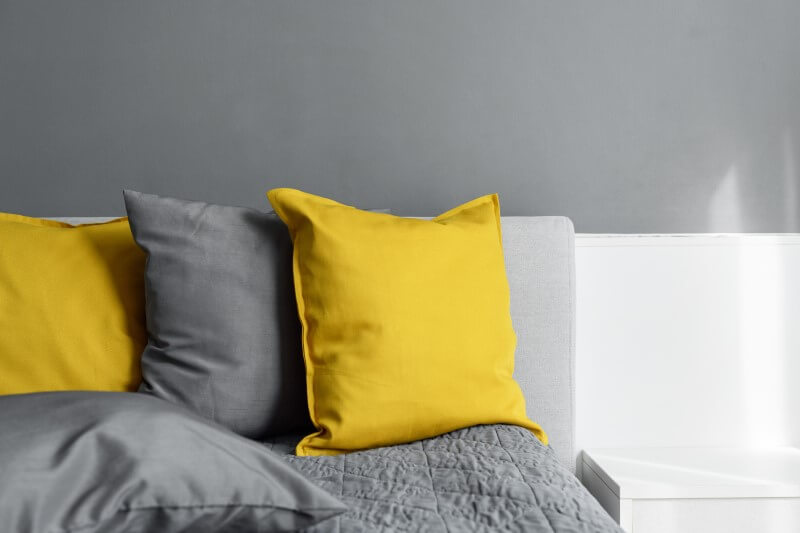 Foto de uma cama com almofadas cinza e amarelo | Pantone 2021 | Decoração | Blog da Tenda
