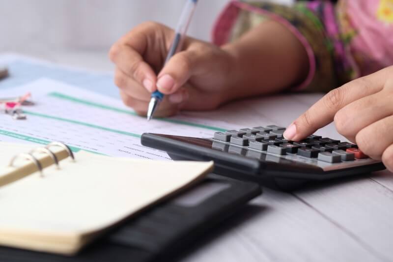Como pagar a entrada do financiamento de imóvel | Foto de uma mulher fazendo contas na calculadora | Guia da Tenda | Blog da Tenda