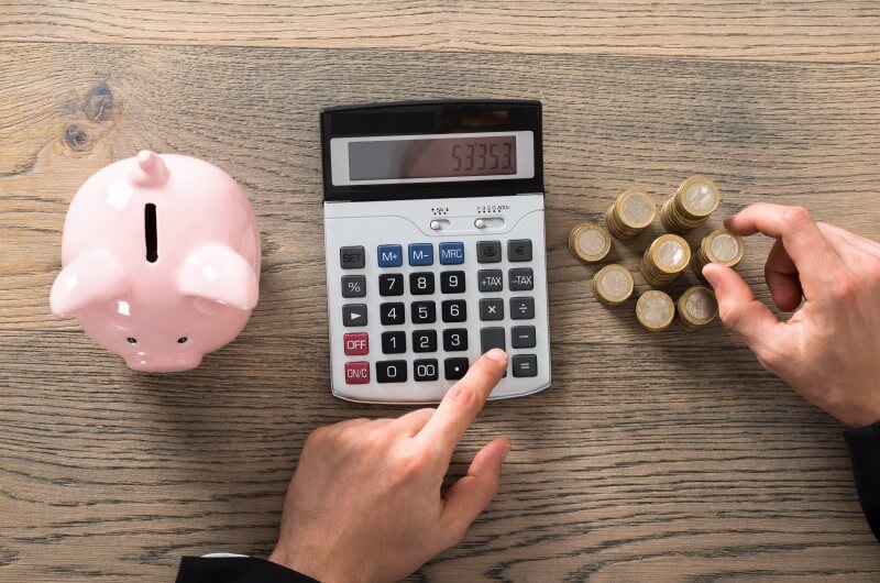 Foto de uma calculadora, moedas e um cofrinho | Valor mínimo para financiar um imóvel | Guia da Tenda | Blog da Tenda