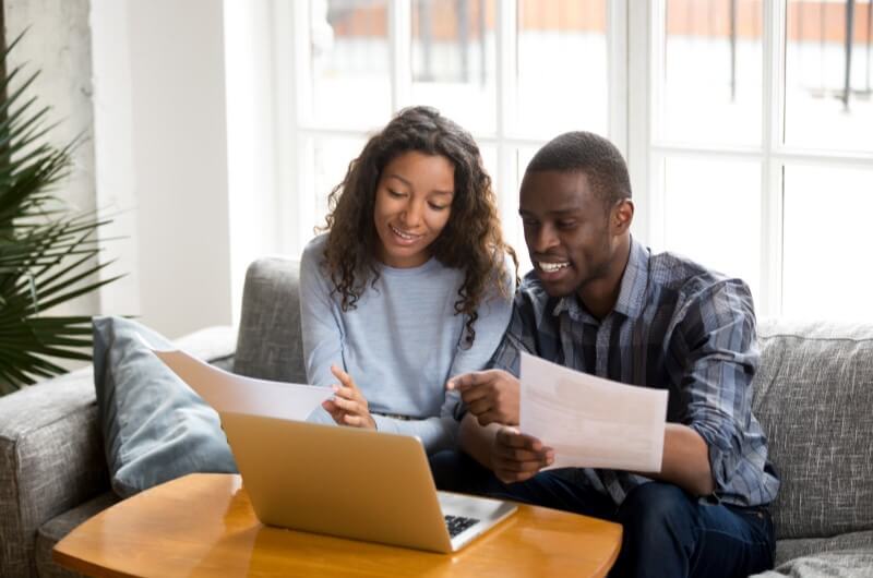 Foto de um casal afrodescente conferindo documentos no computador | Quais documentos para usar o FGTS na compra de apartamento? | Blog da Tenda