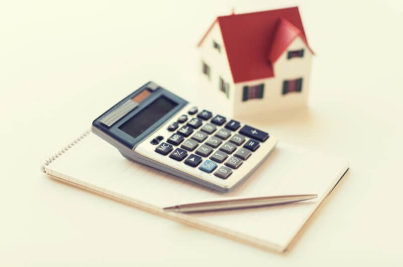 Foto de uma calculadora e uma casinha | Como funciona o pagamento de condomínio | Morar em condomínio | Blog da Tenda