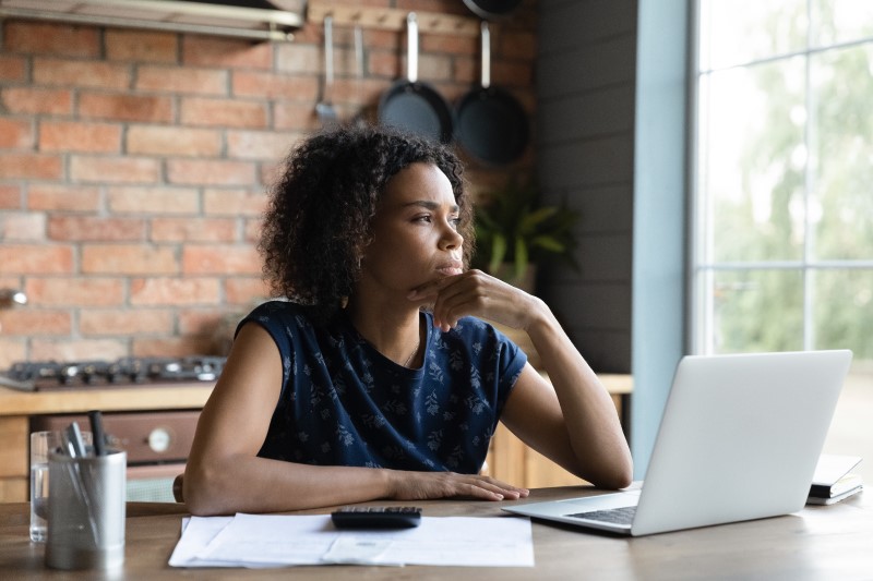 Foto de uma mulher negra com pensando na frente do computador | Em quantas vezes posso parcelar o financiamento de imóvel | Guia da Tenda | Blog da Tenda