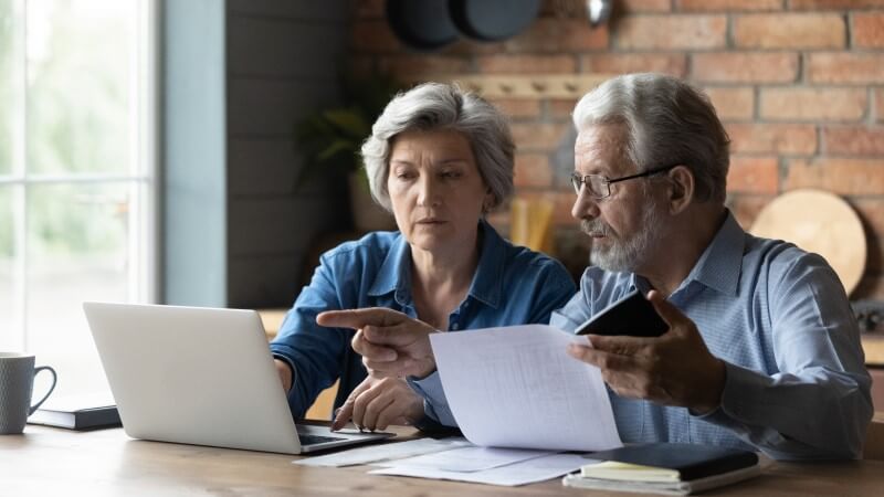 Foto de um casal de aposentados calculando contas | O que é Imposto Predial e Territorial Urbano? | Blog da Tenda