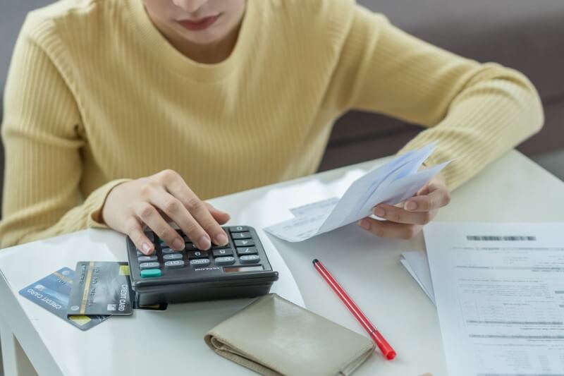 Foto de pessoa calculando as contas | Como devo anotar as minhas dívidas | Economize | Blog da Tenda