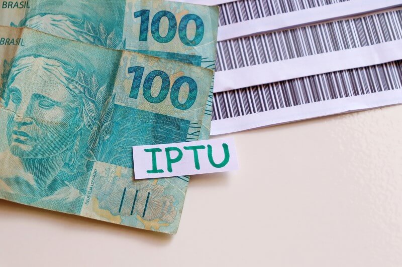Foto de dinheiro e boletos de IPTU | Quais são os principais débitos de início de ano | Economize | Blog da Tenda