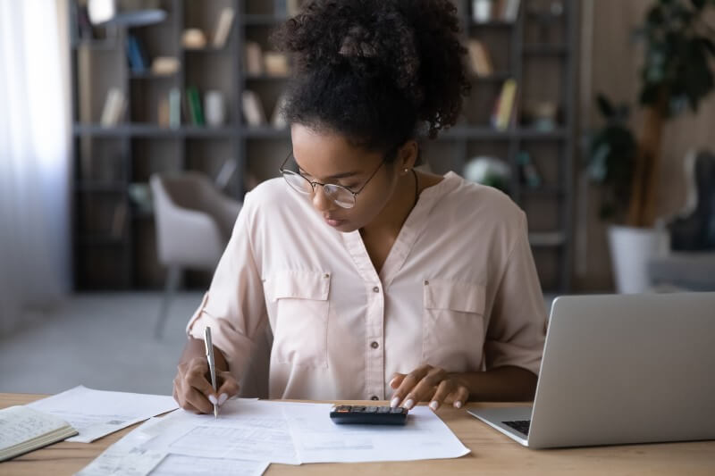 Foto de mulher negra calculando as dívidas | Como posso organizar minhas finanças | Economize | Blog da Tenda