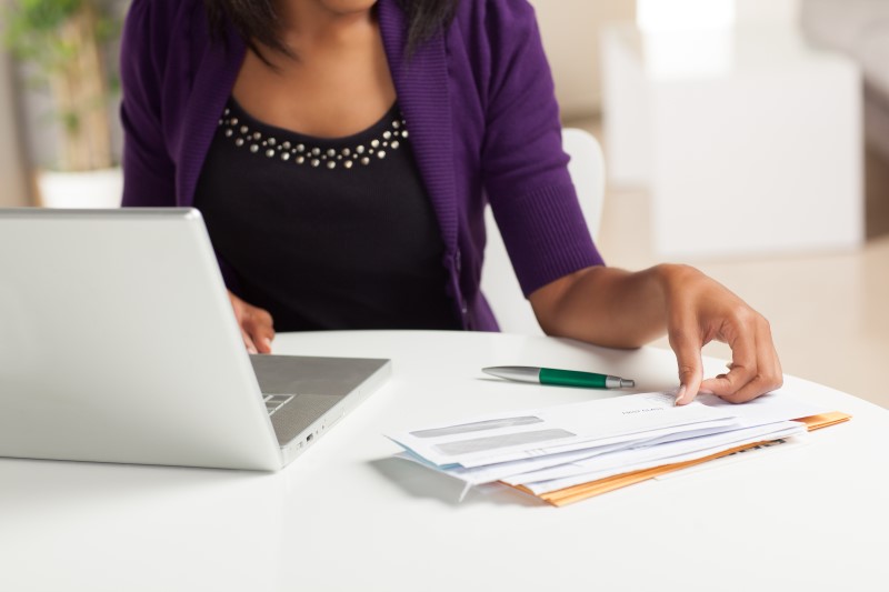Foto de uma mulher negra pagando as contas pelo notebook | Qual o salário para financiar um imóvel | Guia da Tenda | Blog da Tenda