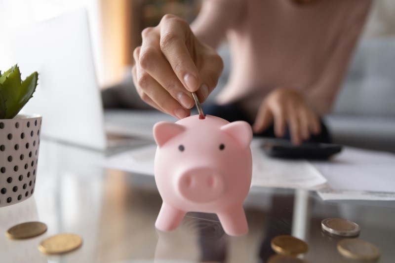 Foto de uma mulher colocando moeda no cofrinho de porquinho | Como começar a ajuntar dinheiro para comprar um apartamento | Guia da Tenda | Blog da Tenda