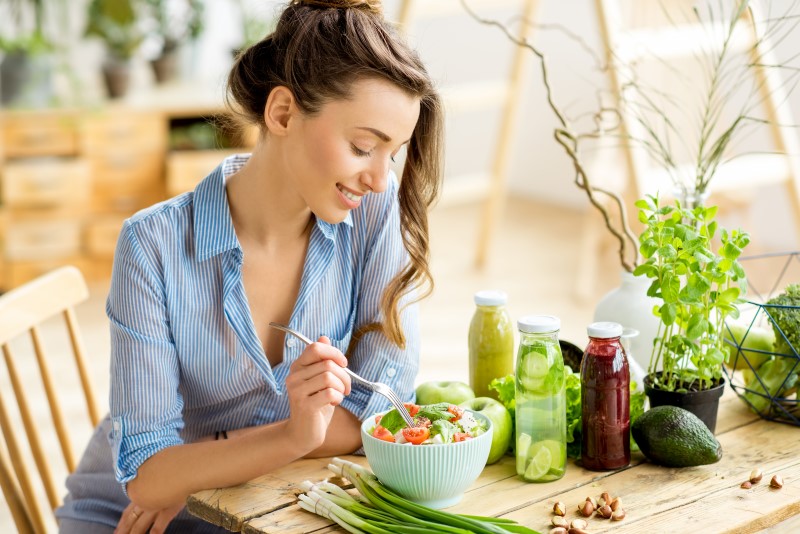 Foto de uma moça comendo salada | Como mudar os hábitos alimentares para morar sozinho | Guia da Tenda | Blog da Tenda