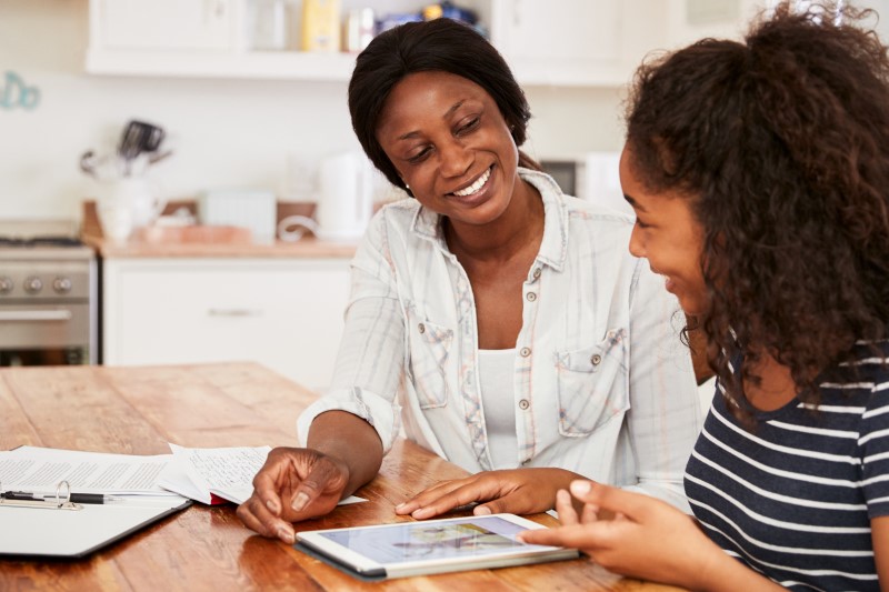 Foto de mãe e filha negras conversando e sorrindo | Como conversar com os pais para sair de casa e morar sozinho | Guia da Tenda | Blog da Tenda