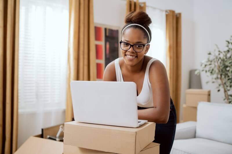 Foto de uma moça negra feliz de mudança para novo apartamento | Como comprar um apartamento sozinha | Guia da Tenda | Blog da Tenda