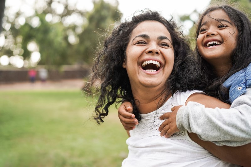 Foto de uma mãe e uma filha sorrindo no parque | Casa Verde e Amarela prioriza famílias chefiadas por mulheres | Minha Casa Minha Vida | Blog da Tenda 
