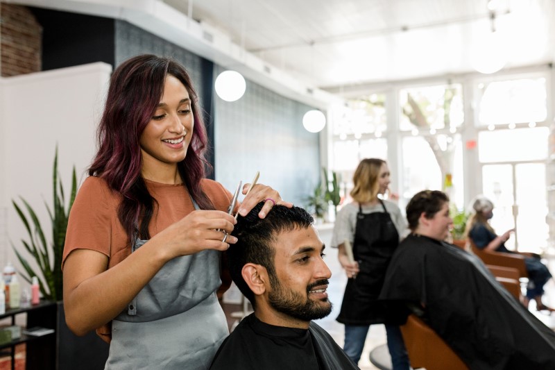 Foto de uma cabelereira cortando o cabelo de um homem | Como comprovar renda sendo autônomo no financiamento de imóveis | Minha Casa Minha Vida | Blog da Tenda