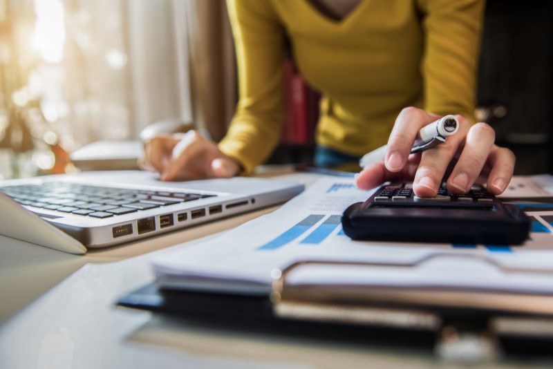 Foto de uma mulher fazendo contas na calculadora | Quanto preciso ter para comprar um apartamento | Guia da Tenda | Blog da Tenda