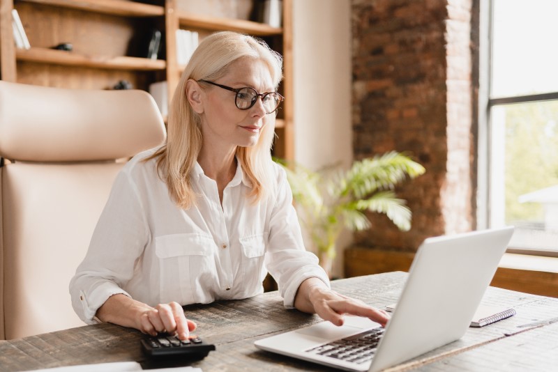 O que é análise de crédito | Foto de uma mulher fazendo as contas na calculadora e no computador | Guia da Tenda | Blog da Tenda
