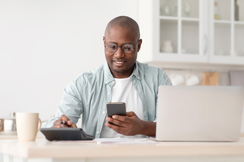 Como poupar dinheiro para comprar um imóvel | Foto de um homem negro fazendo as contas na calculadora | Guia da Tenda | Blog da Tenda