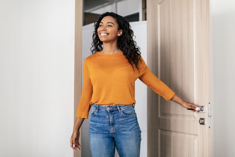 Benefícios de morar em apartamento pequeno | Foto de uma mulher feliz entrando em casa | Guia da Tenda | Blog da Tenda