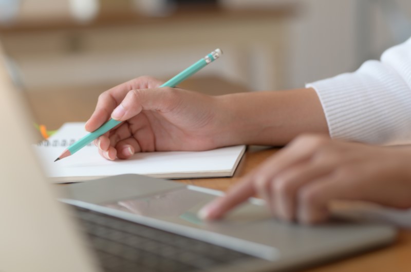 Quanto tempo demora a análise de crédito? | Foto de um pessoa anotando em um caderno e usando o notebook | Dúvidas sobre dívidas | Eu Dou Conta