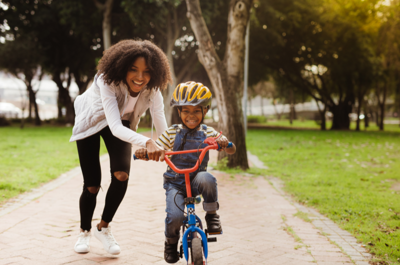 Ciclovias | Foto de uma mãe ajudando seu filho a andar de bicicleta | Trilha da Conquista | Blog da Tenda 