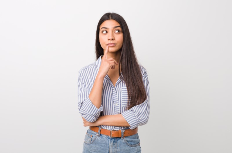 Como comprar um apartamento financiado direto pela construtora? | Foto de uma moça com a mão no queixo e a expressão pensativa | Trilha da Conquista | Blog da Tenda