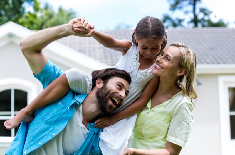 Por que as pessoas escolhem morar na Zona Leste? | Foto de uma familia feliz se divertindo do lado de fora de casa | Trilha da Conquista | Blog da Tenda 