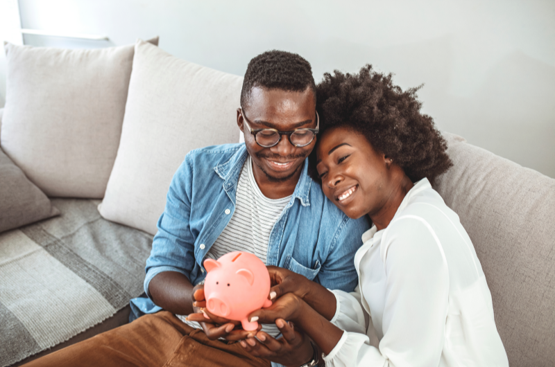 Como usar o FGTS para dar entrada em um apartamento? | Foto de um casal sorridente segurando um cofrinho | Economia e renda extra | Eu Dou Conta