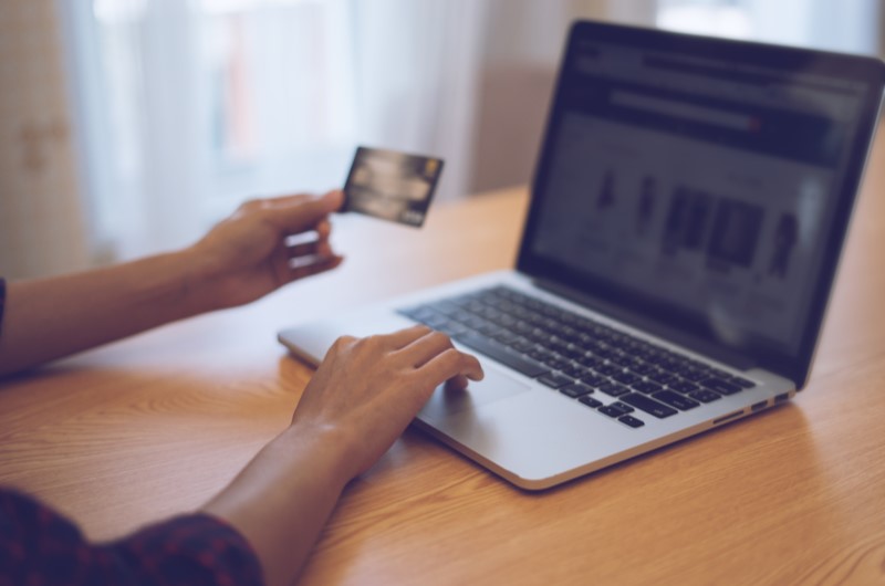 Evite fazer dívidas no cartão de crédito | Foto de uma pessoa usando o notebook e segurando um cartão | Economia e renda extra | Eu Dou Conta