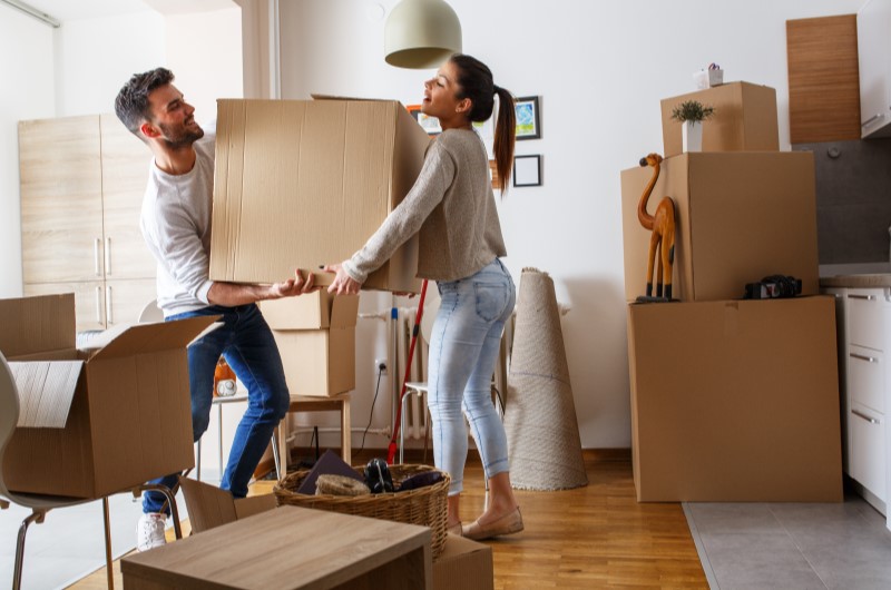 O que comprar para a casa nova? | Foto de um casal segurando uma caixa de mudança na casa nova | Casa e Decoração | Blog da Tenda