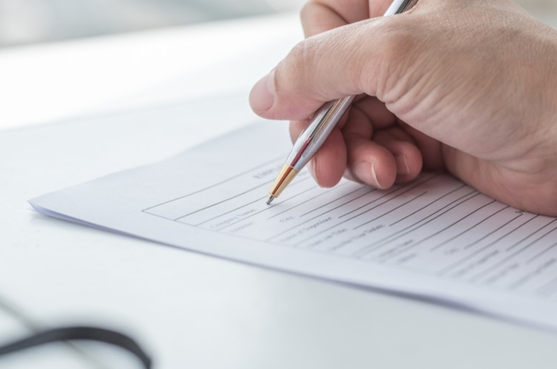 Qual a importância? | Foto de uma mão assinando escrevendo em um papel | Tenda Explica | Blog da Tenda