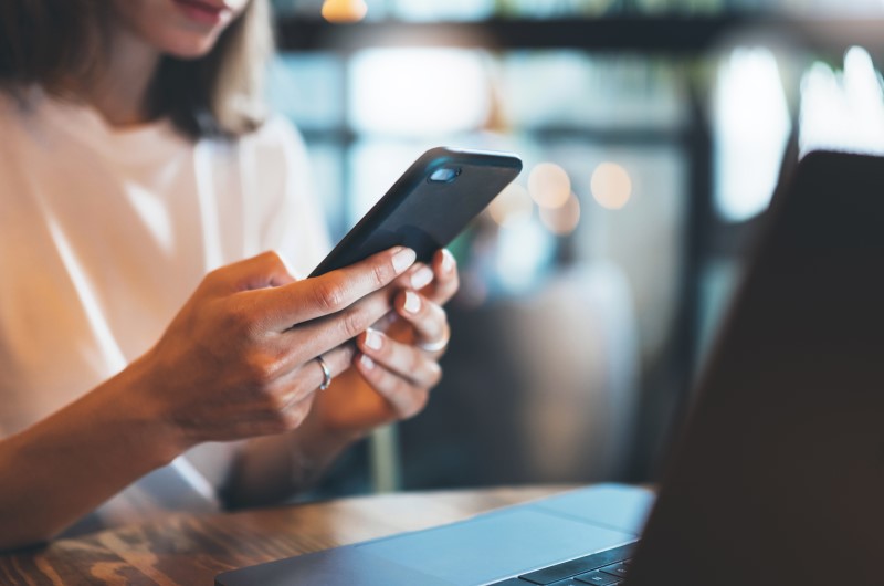 Quando vale a pena pedir um empréstimo para quitar as dívidas? | Foto de uma moça usando o celular | Dúvidas sobre dívidas | Eu Dou Conta