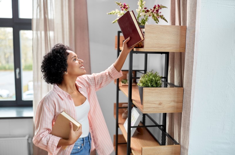 Avalie a necessidade e funcionalidade de cada móvel | Foto de uma moça organizando a decoração de uma estante | Casa e Decoração | Blog da Tenda