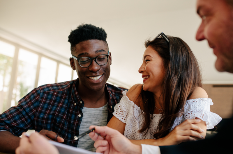 Como funciona a compra de um apartamento? | Foto de uma casal sorridente conversando com um corretor | Trilha da Conquista | Blog da Tenda