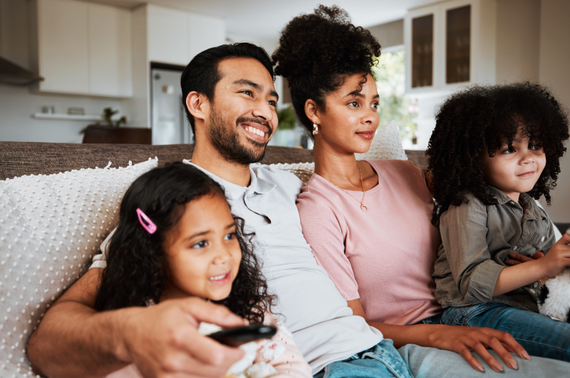 O que saber antes de comprar um apartamento: defina as suas necessidades e de sua família | Foto de uma família feliz reunida no sofá da sala | Trilha da Conquista | Blog da Tenda