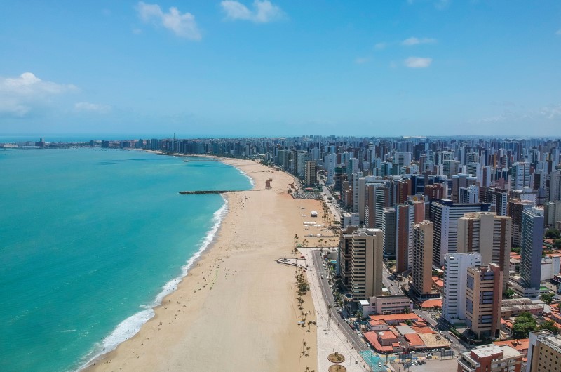 Como é morar em Fortaleza | Foto da vista aérea de Fortaleza, mostrando um céu azul, o mar e a cidade | Trilha da Conquista | Blog da Tenda