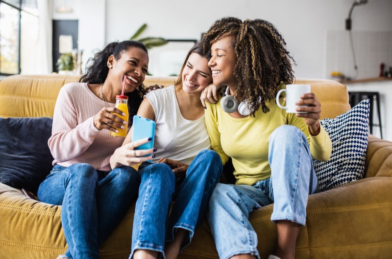 Poder escolher seu vizinho | Foto de três amigas sorridentes se divertindo na sala de estar | Tenda Explica | Blog da Tenda