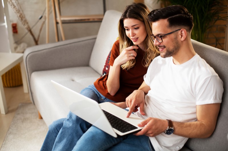 Benefícios de participar do programa | Foto de um casal sentado no sofá enquanto usa o notebook | Blog da Tenda