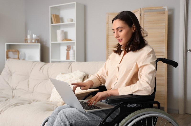 Que tipos de imóveis podem ser financiados pelo Programa? | Foto de uma moça em cadeira de rodas pesquisando no notebook | Trilha da Conquista | Blog da Tenda 