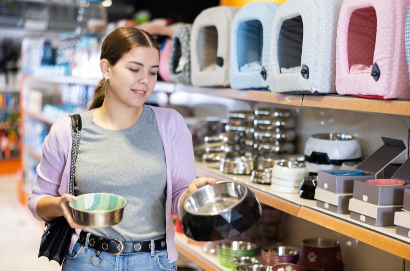 Higiene e cuidados: dicas essenciais para manter seu bichinho | Foto de uma mulher em um petshop comprando potes para animais | Viver em condomínio | Blog da Tenda