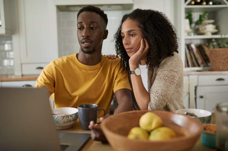 O que é a compra conjunta de imóvel? | Foto de um casal concentrado em olhar para o notebook | Trilha da Conquista | Blog da Tenda