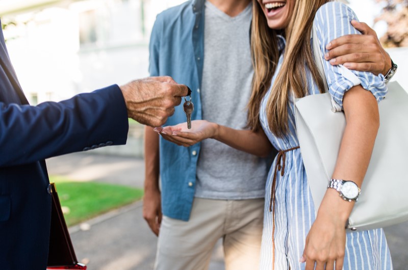 O que é o Programa Porta de Entrada? | Corretor de imóveis entregando chaves a um casal feliz | Minha Casa Minha Vida | Blog da Tenda