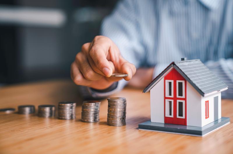 Quais são as taxas de juros do programa? | Homem organizando moedas ao lado de uma casinha | Minha Casa Minha Vida | Blog da Tenda 