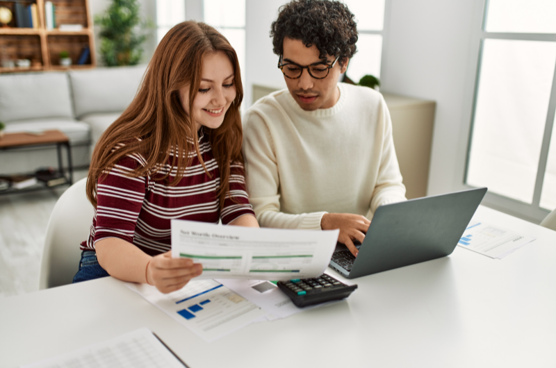 Como quitar financiamento imobiliário mais rápido | Casal olhando para um documento enquanto usa o notebook | Eu Dou Conta | Blog da Tenda 