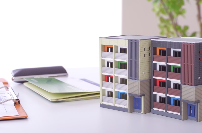 O subsíndico pode substituir o síndico | Miniatura de um prédio de apartamentos ao lado de documentos | Viver em Condomínio | Blog da Tenda 